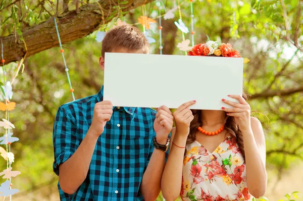 Pár dívka a muž s bílou cedulí v ruce — Stock fotografie