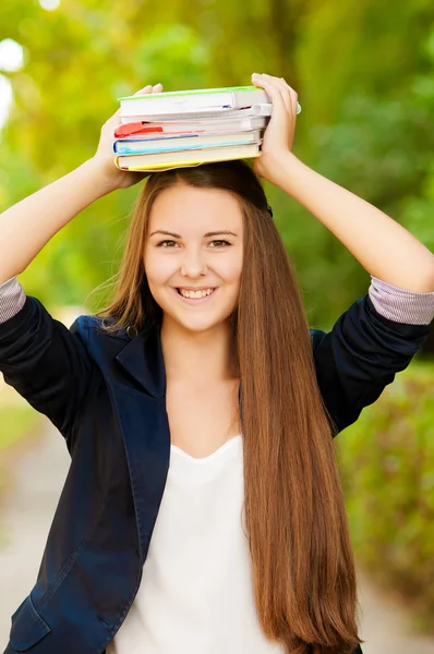 Adolescente studentessa tenendo libri sulla sua testa — Foto Stock