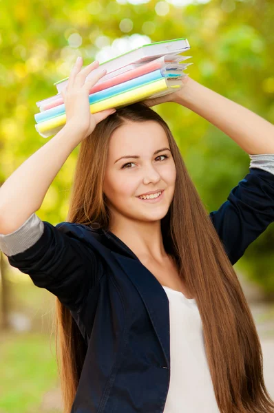 Adolescente estudiante chica sosteniendo libros en su cabeza —  Fotos de Stock