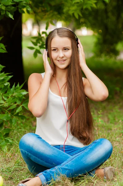 十几岁的女孩，戴着耳机在树附近 — 图库照片