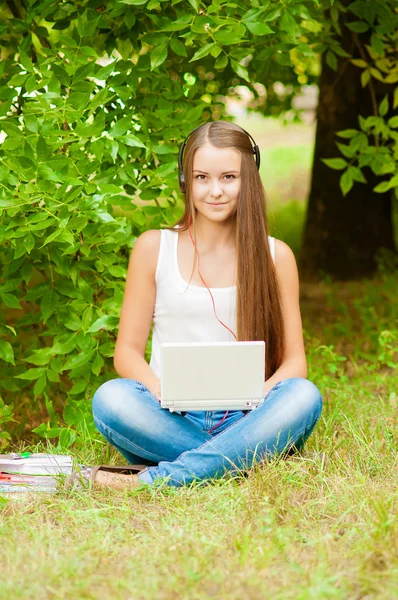 Menina adolescente trabalha com o laptop na grama — Fotografia de Stock