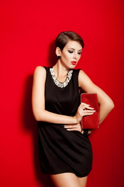 Beautiful girl with a red clutch bag — Stock Photo, Image