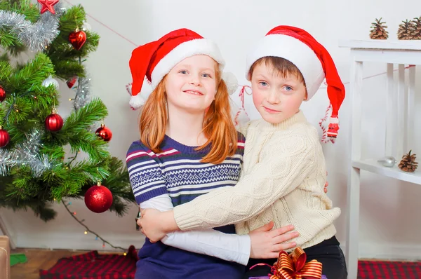 Enfants près d'un sapin de Noël avec des cadeaux — Photo