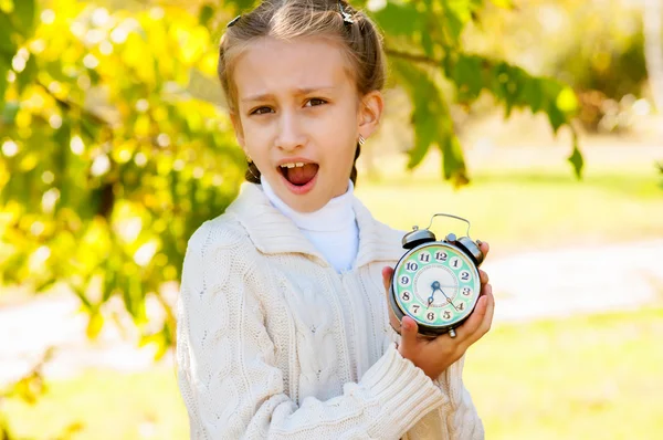 Meisje met een klok in zijn handen in het park — Stockfoto