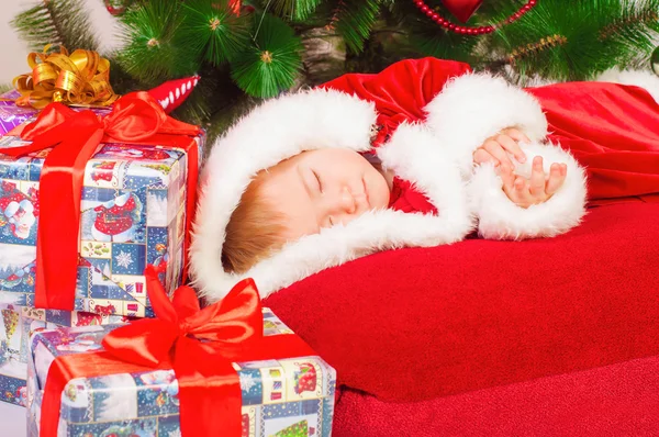 Bebê em Santa fantasia dormindo na árvore de Natal — Fotografia de Stock