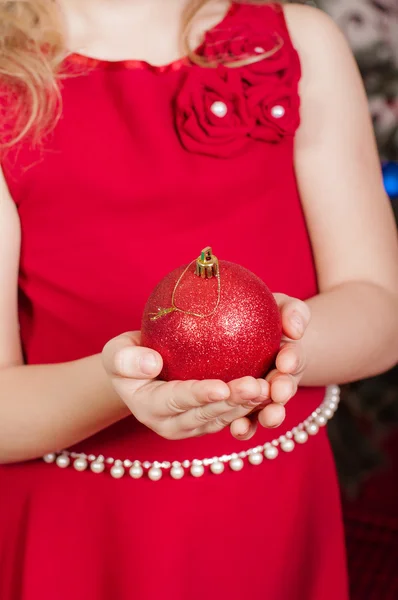 Weihnachtsball in den Händen eines kleinen Mädchens — Stockfoto