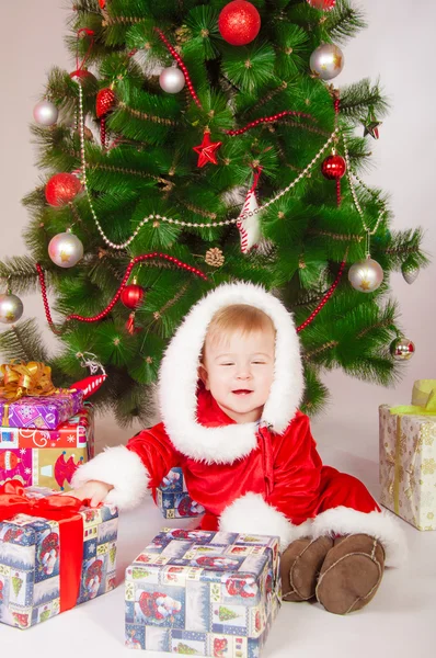 Bébé en costume de Père Noël au sapin de Noël avec des cadeaux — Photo