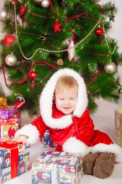 Baby in Santa costume at the Christmas tree with gifts — Stock Photo, Image