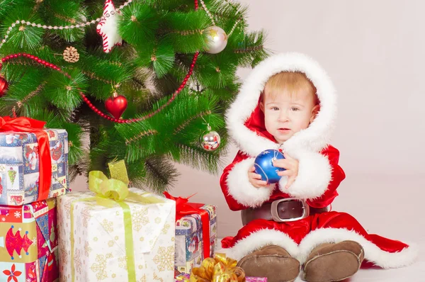 Baby i Santa dräkt på granen med gåvor — Stockfoto