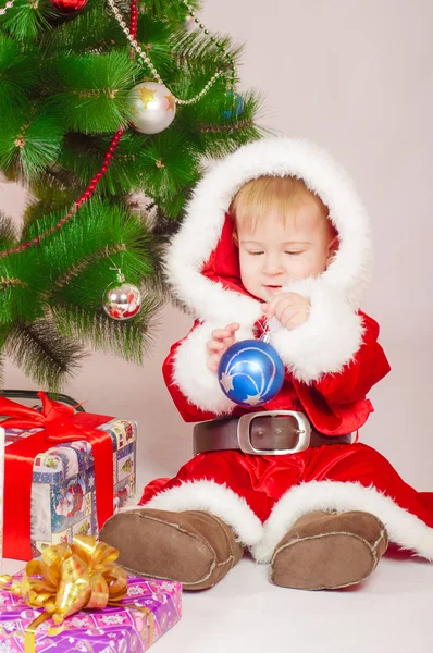 Baby in Santa costume at the Christmas tree with gifts — Stock Photo, Image