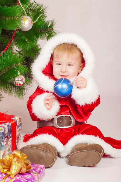 Baby in Santa costume at the Christmas tree with gifts — Stock Photo, Image