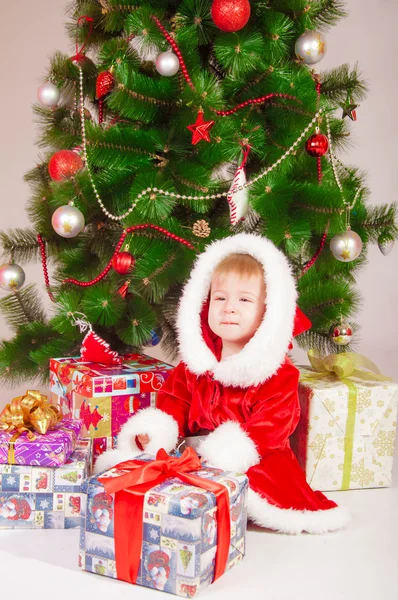 Baby i Santa dräkt på granen med gåvor — Stockfoto