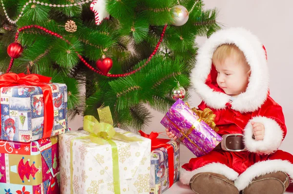 Baby i Santa dräkt på granen med gåvor — Stockfoto