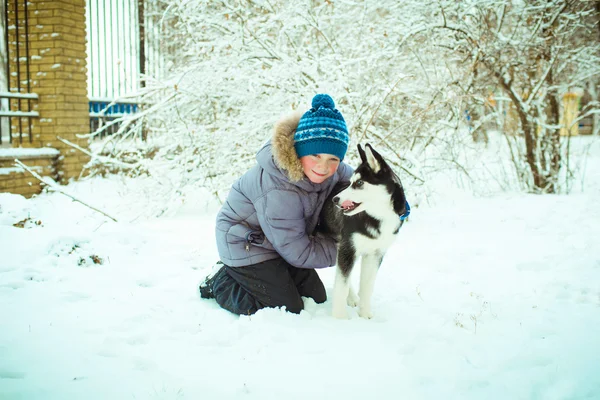 Liten pojke med Husky hund på snö — Stockfoto