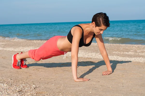 Junge schöne Sportlerin am Strand — Stockfoto