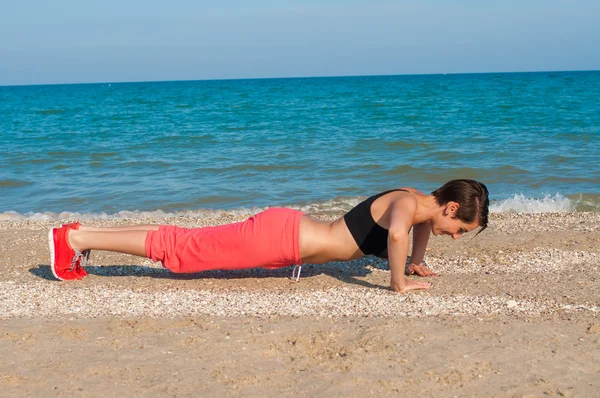 Young beautiful girl athlete on the beach — Stock Photo, Image