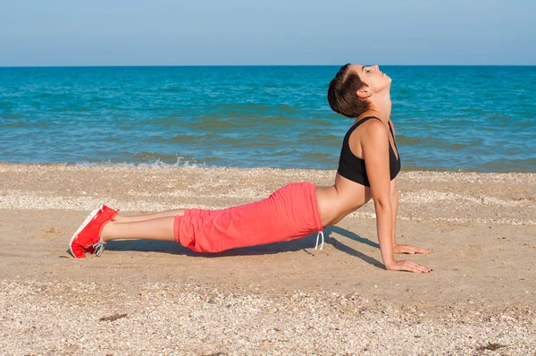 Junge schöne Sportlerin am Strand — Stockfoto