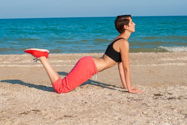 Young beautiful girl athlete on the beach — Stock Photo, Image