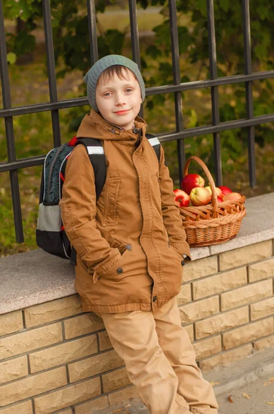 Pojke med en skola ryggsäck med en korg med äpplen — Stockfoto