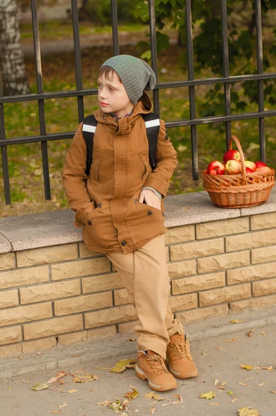 Pojke med en skola ryggsäck med en korg med äpplen — Stockfoto