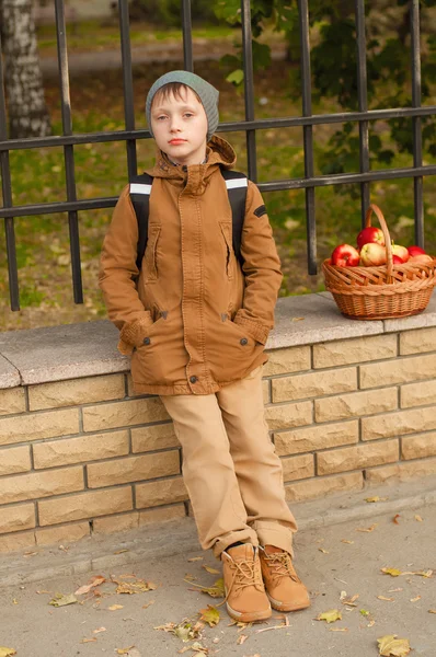 Menino com uma mochila escolar com uma cesta de maçãs — Fotografia de Stock