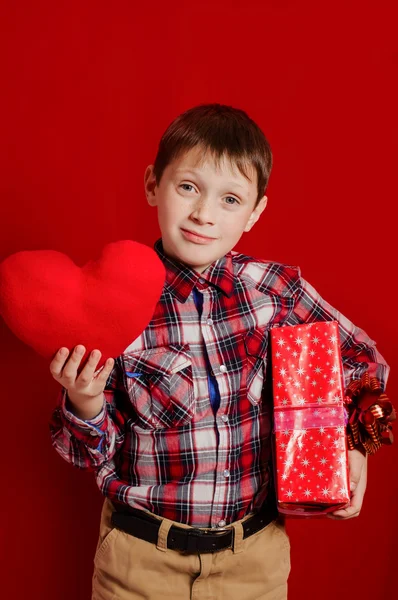 Menino com um coração de brinquedo e caixa de presente — Fotografia de Stock