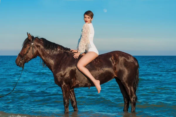 Jeune belle fille avec un cheval sur la plage — Photo