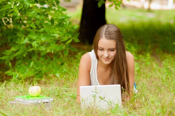 Menina adolescente trabalha com o laptop na grama — Fotografia de Stock