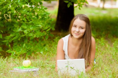 genç kız ile laptop çimenlerin üzerinde çalışır.