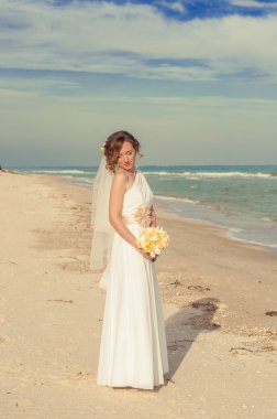 Sahilde bir buket ile güzel elbiseli genç gelin