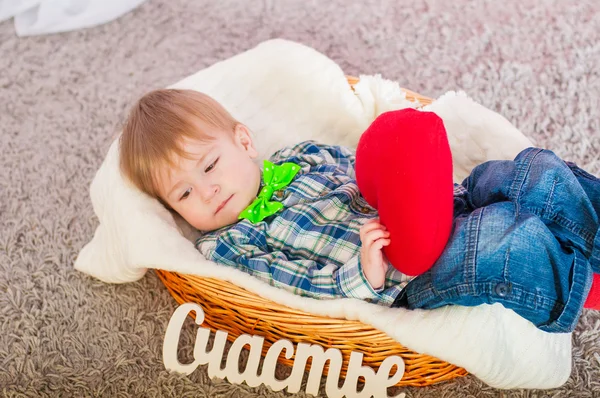 Kleine jongen ligt in een mand met speelgoed hart — Stockfoto