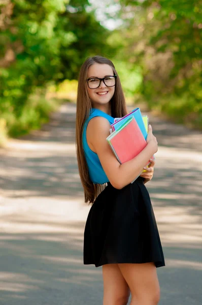 Tiener meisje met glazen en boeken in handen — Stockfoto