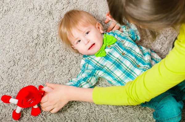 Kind strikje ligt op het tapijt — Stockfoto