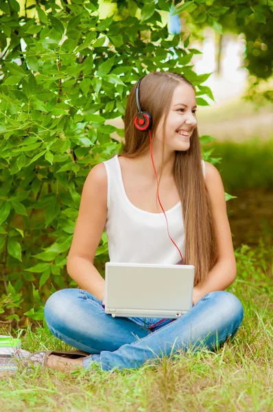 Teen ragazza lavora con il computer portatile sull'erba — Foto Stock