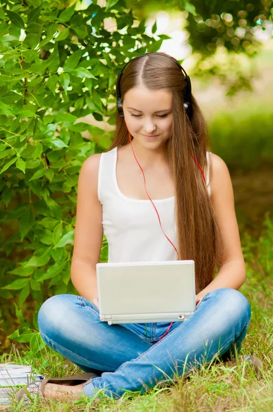Девушка-подросток работает с ноутбуком на траве — стоковое фото