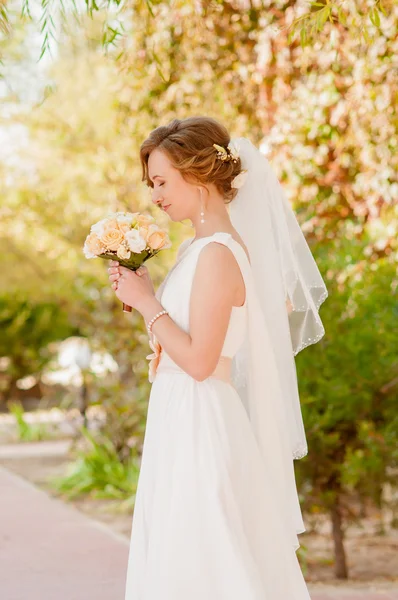 Junge Braut im Garten in einem weißen Kleid — Stockfoto