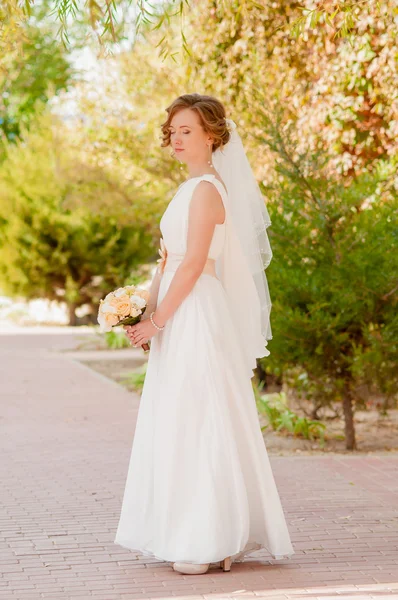 Young bride in a garden in a white dress — Stock Photo, Image