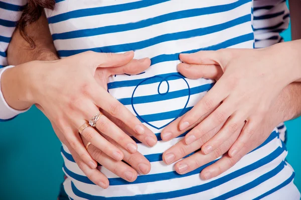 Handen van mannen en vrouwen op de buik van een zwangere vrouw — Stockfoto