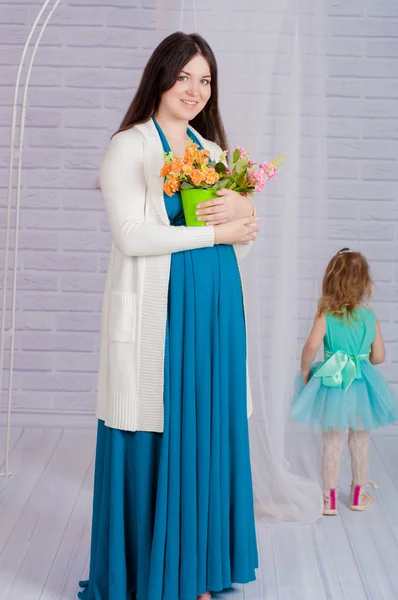Jovem mulher grávida em um vestido turquesa e menina — Fotografia de Stock