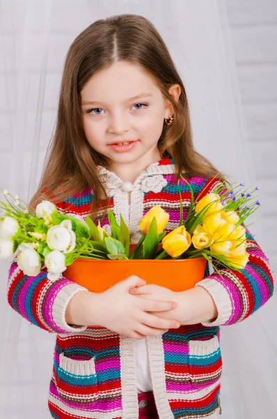 Kleines Mädchen mit Frühlingsblumen in der Vase — Stockfoto