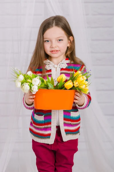 Kleines Mädchen mit Frühlingsblumen in der Vase — Stockfoto