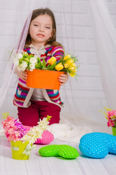 Kleines Mädchen mit Frühlingsblumen in der Vase — Stockfoto