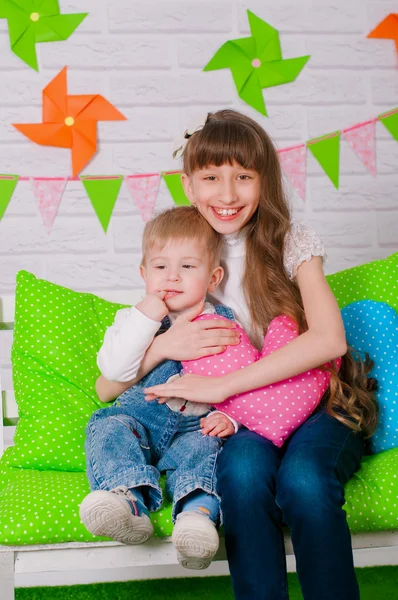 Malý chlapec a starší sestra, usmívající se na lavičce — Stock fotografie