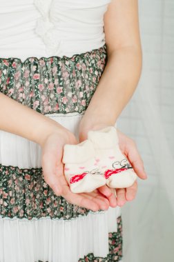 Baby socks in  hands of pregnant woman clipart