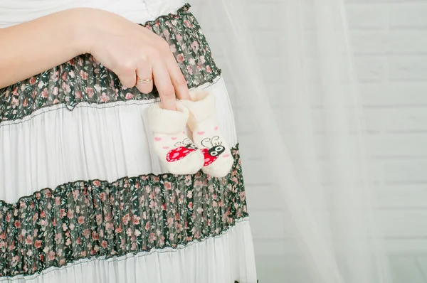 Babysocken in den Händen einer schwangeren Frau — Stockfoto