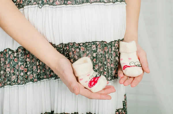 Chaussettes bébé dans les mains de la femme enceinte — Photo