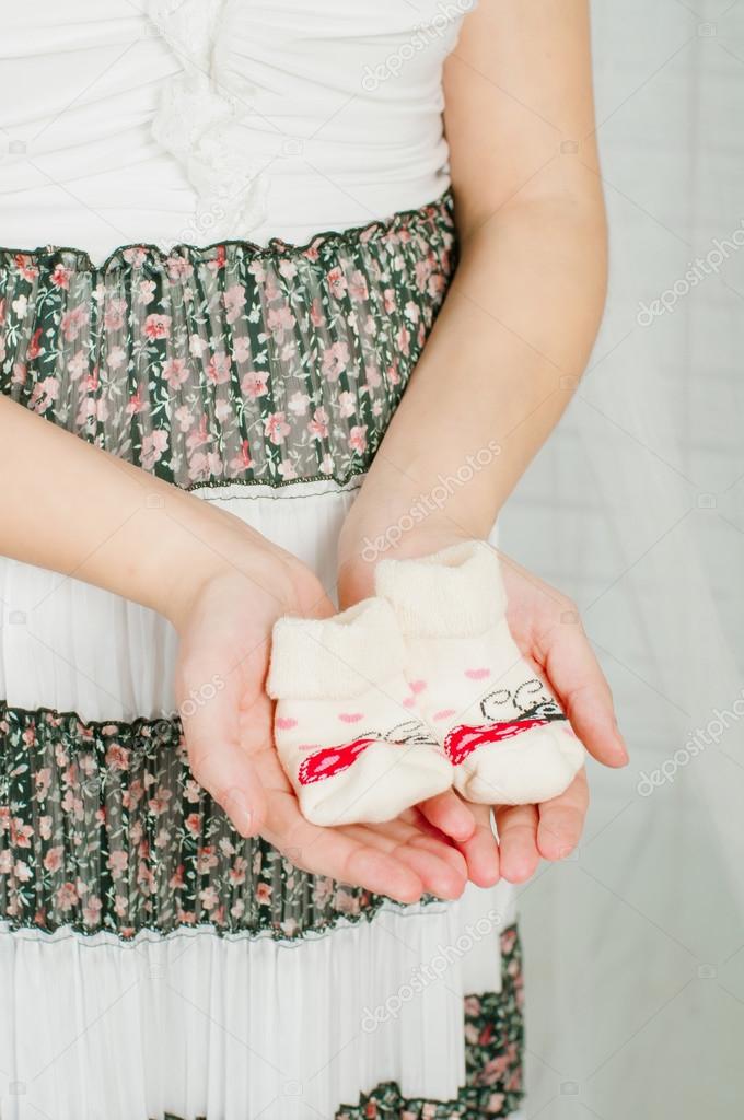 Baby socks in  hands of pregnant woman