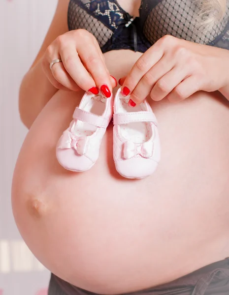 Meias de bebê em mãos de mulher grávida — Fotografia de Stock