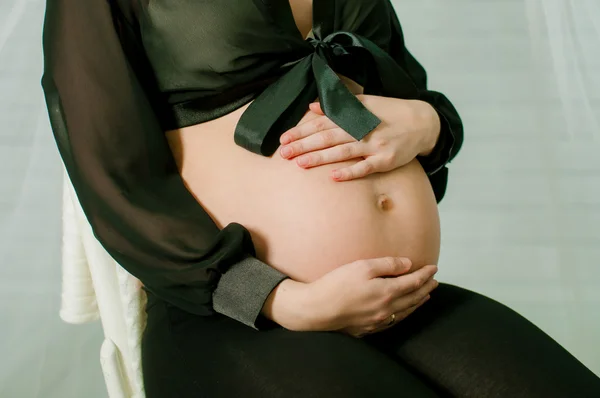 Händerna på en gravid kvinna på mage — Stockfoto