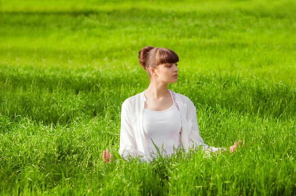 Jeune fille faisant du yoga sur une herbe verte — Photo